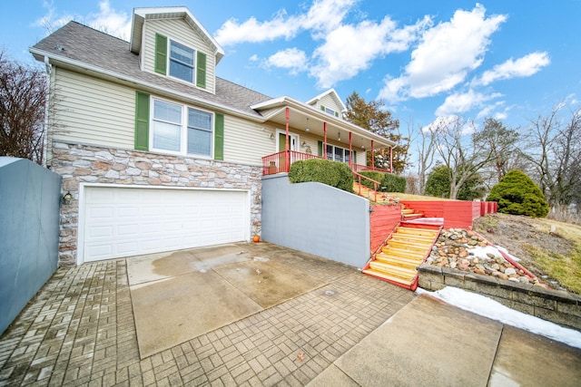 view of front of home with stone siding, stairway, an attached garage, and driveway