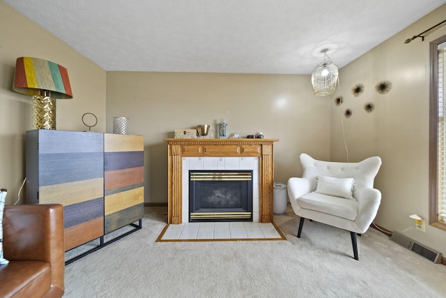 living area featuring visible vents, baseboards, carpet, a textured ceiling, and a fireplace