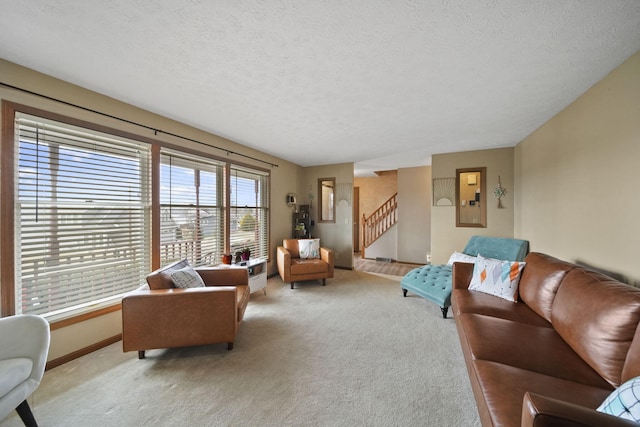 carpeted living area featuring a textured ceiling, baseboards, and stairs