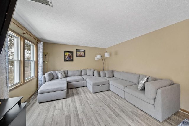 living room featuring a textured ceiling, visible vents, and light wood-style floors