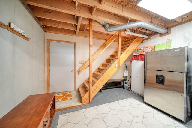 finished basement with carpet, stairway, and freestanding refrigerator