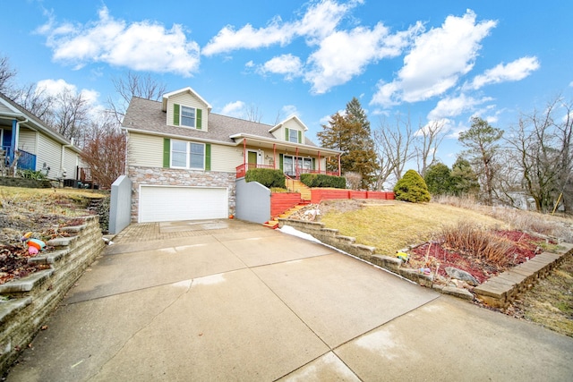 view of front facade featuring roof with shingles, covered porch, concrete driveway, a garage, and stone siding