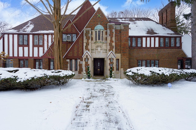 english style home featuring brick siding and a chimney