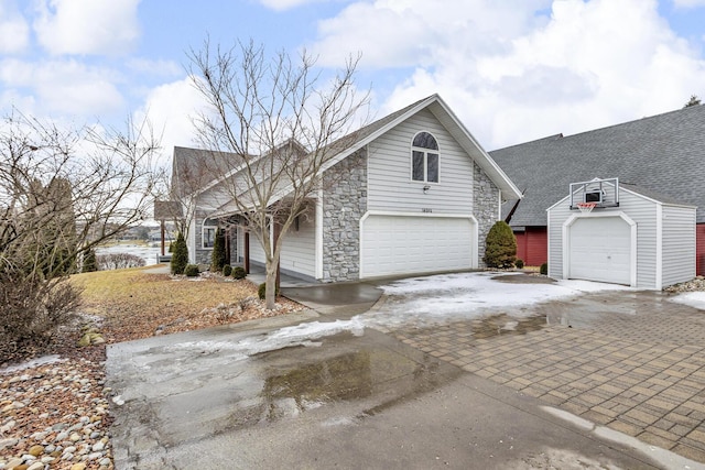 view of front of house featuring a shingled roof, stone siding, driveway, and an attached garage