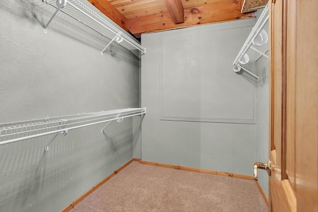 walk in closet with carpet flooring and beamed ceiling