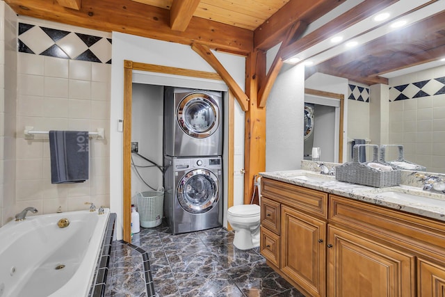 bathroom featuring toilet, stacked washer and dryer, a tub with jets, and a sink