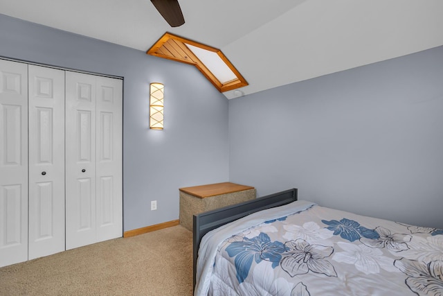 carpeted bedroom featuring lofted ceiling with skylight, a closet, and ceiling fan