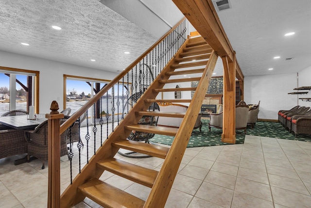 staircase featuring recessed lighting, visible vents, a textured ceiling, and tile patterned floors