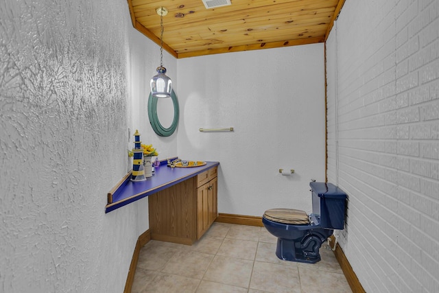 bathroom with wooden ceiling, toilet, brick wall, vanity, and tile patterned floors