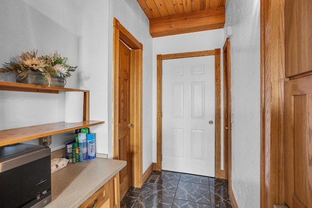 entryway featuring marble finish floor, beam ceiling, wood ceiling, and baseboards