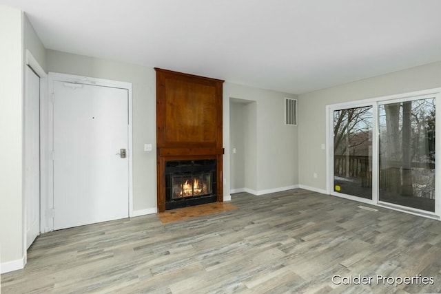 unfurnished living room featuring a large fireplace, baseboards, visible vents, and light wood-style floors