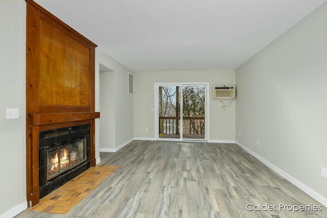 unfurnished living room with baseboards, a fireplace, and light wood-style floors