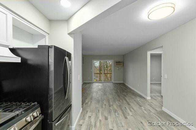 kitchen featuring baseboards, white cabinets, light wood-style flooring, freestanding refrigerator, and premium range hood