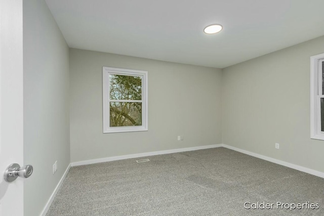 unfurnished room with carpet floors, visible vents, and baseboards