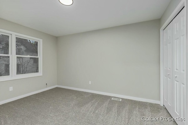 unfurnished bedroom with a closet, carpet flooring, visible vents, and baseboards