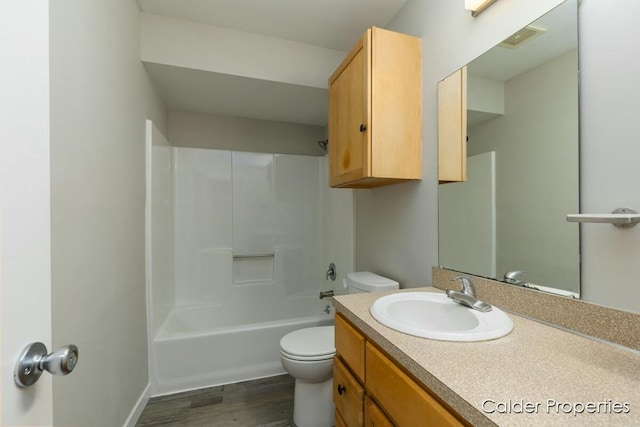 bathroom featuring visible vents, toilet, wood finished floors, vanity, and shower / bathing tub combination