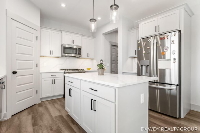 kitchen featuring a center island, stainless steel appliances, backsplash, white cabinets, and wood finished floors