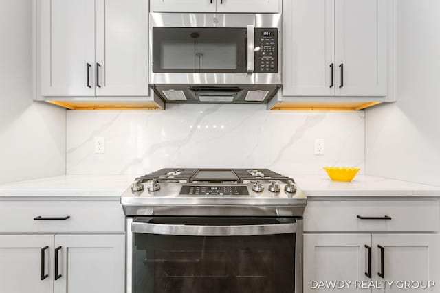 kitchen with light stone countertops, tasteful backsplash, and appliances with stainless steel finishes