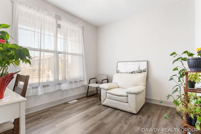 living area featuring wood finished floors, visible vents, and baseboards