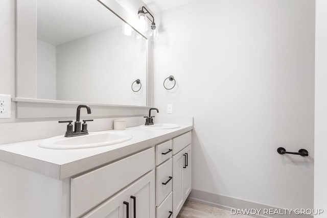 full bathroom with double vanity, a sink, and baseboards