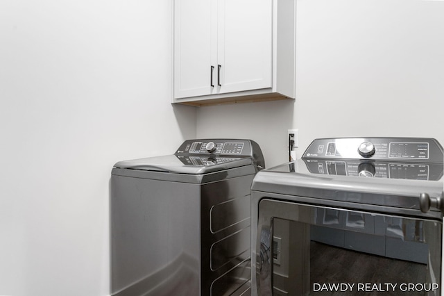 laundry room with wood finished floors, washing machine and dryer, and cabinet space