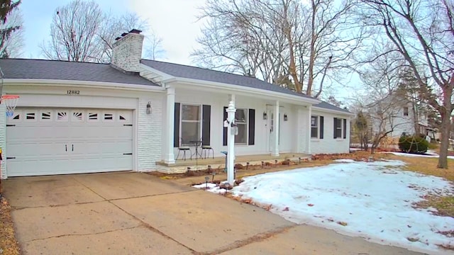 ranch-style home with a porch, an attached garage, brick siding, concrete driveway, and a chimney