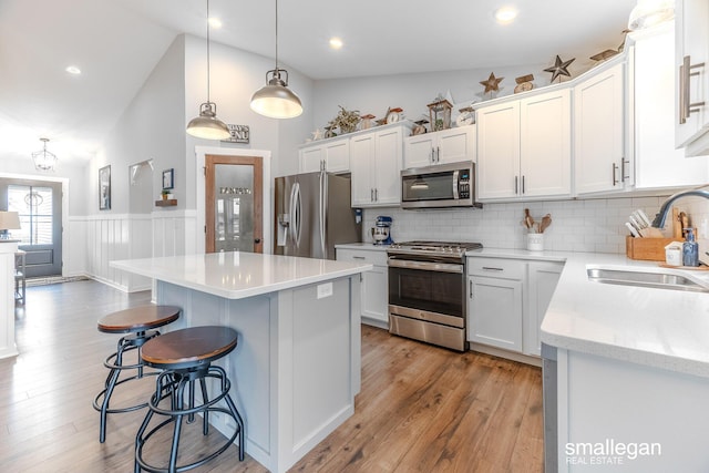 kitchen with light wood-style flooring, stainless steel appliances, a breakfast bar, a kitchen island, and a sink