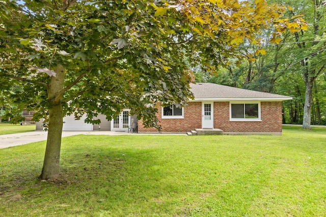 view of front facade featuring french doors, brick siding, an attached garage, a front yard, and driveway