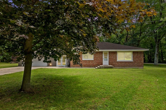 view of front facade with concrete driveway, an attached garage, french doors, a front lawn, and brick siding