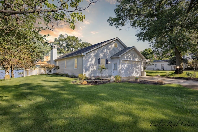 view of front of home featuring a chimney, concrete driveway, a lawn, an attached garage, and fence