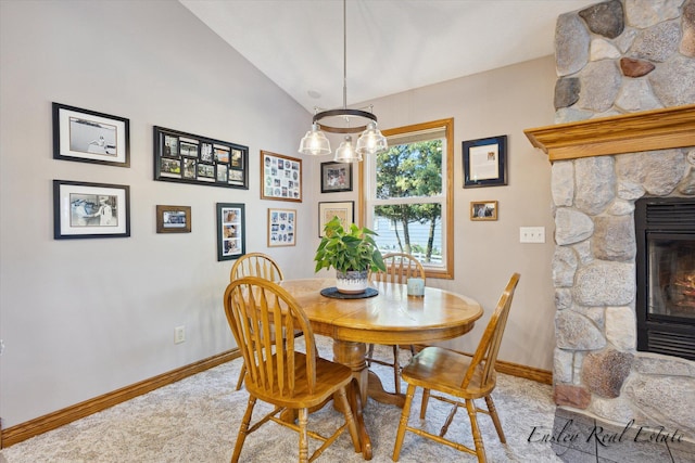 dining space with a fireplace, baseboards, vaulted ceiling, and light colored carpet