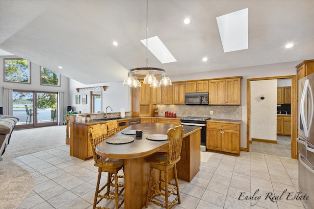 kitchen with stainless steel appliances, a peninsula, a skylight, a sink, and open floor plan