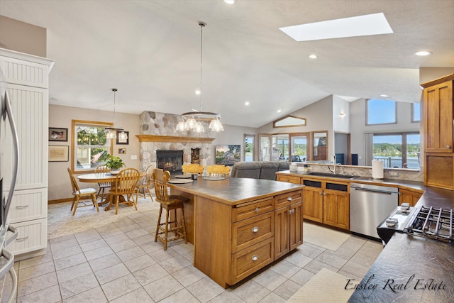 kitchen featuring brown cabinets, a fireplace, open floor plan, and stainless steel dishwasher