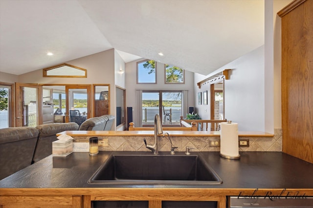 kitchen featuring dark countertops, high vaulted ceiling, open floor plan, and a sink