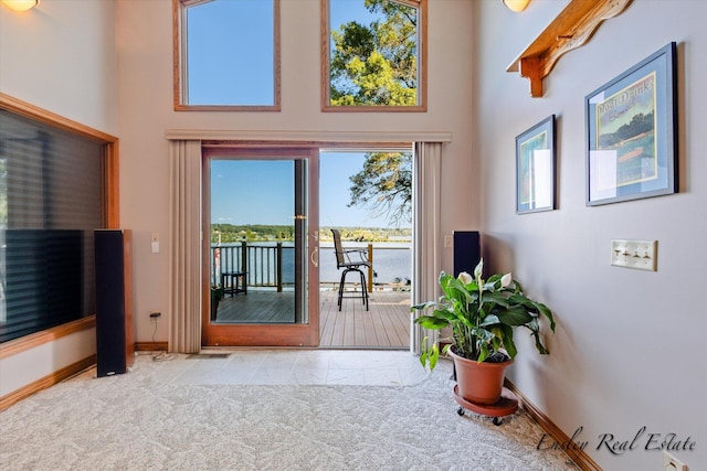 doorway to outside with carpet floors, a towering ceiling, and baseboards