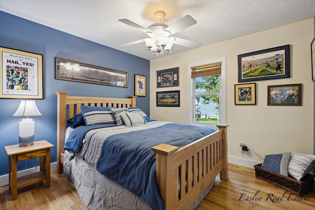 bedroom featuring a ceiling fan, a textured ceiling, baseboards, and wood finished floors