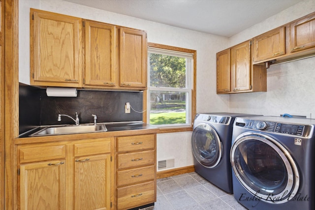 laundry area featuring cabinet space, visible vents, a sink, and washer and clothes dryer