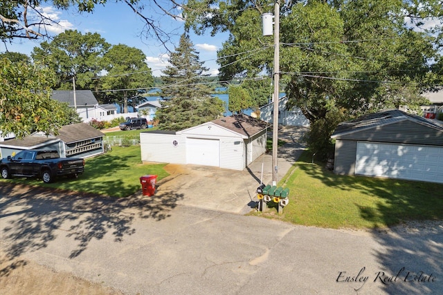 single story home featuring a garage, a front lawn, and an outbuilding