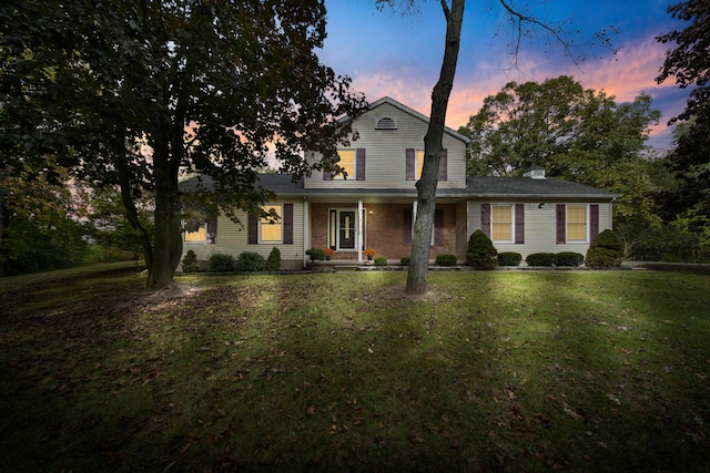 traditional home featuring brick siding and a yard