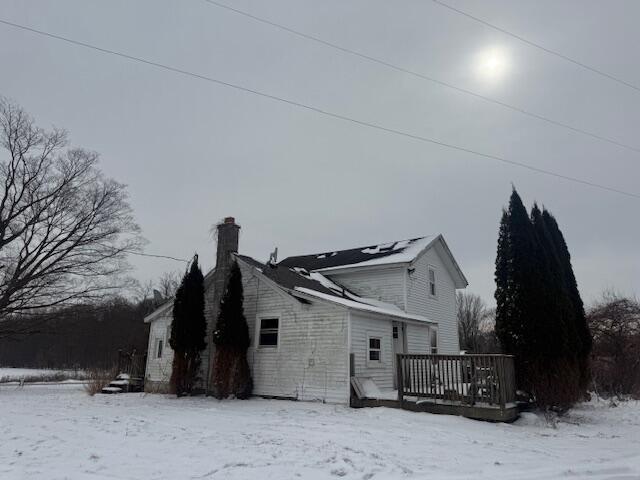 view of snowy exterior featuring a chimney and a deck