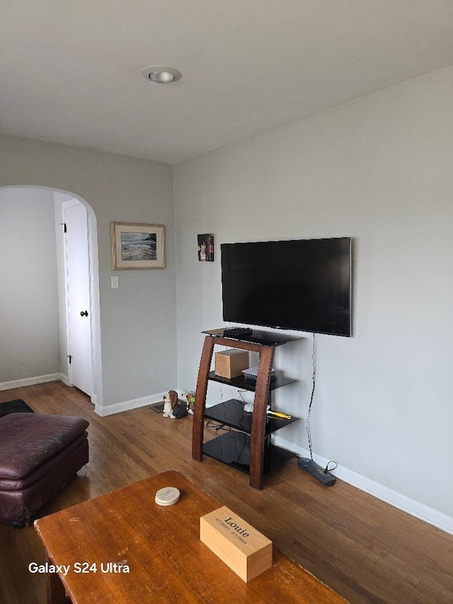 living room with baseboards, arched walkways, and wood finished floors