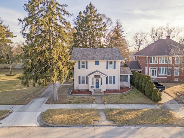 view of front facade with concrete driveway, a front lawn, and roof with shingles