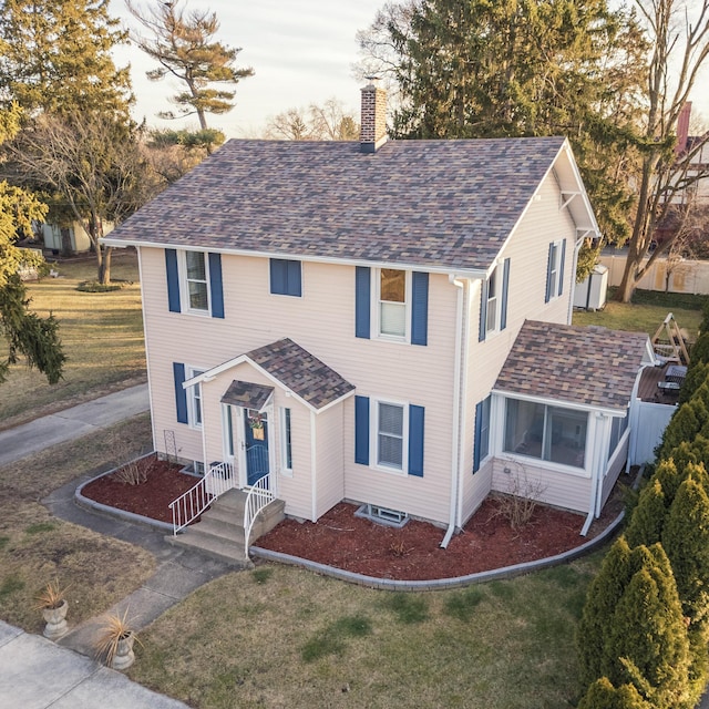 view of front facade with a shingled roof, a chimney, and a front lawn