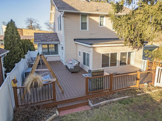 rear view of house with a shingled roof, fence, and a wooden deck