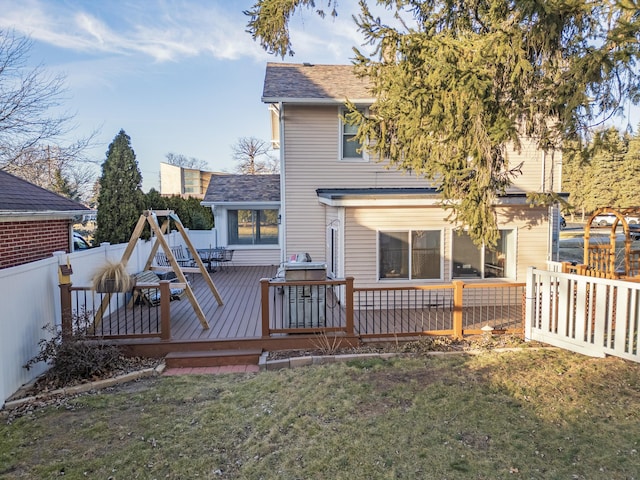 back of property featuring a shingled roof, a fenced backyard, a lawn, and a deck