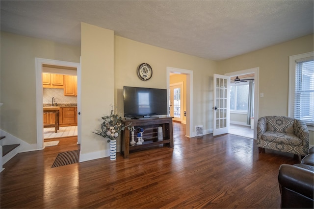 living area with dark wood-type flooring, visible vents, baseboards, stairs, and french doors