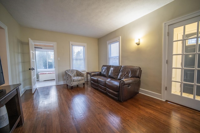 living room featuring a textured ceiling, baseboards, and hardwood / wood-style flooring