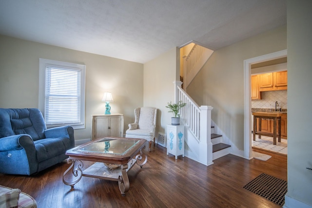 living area with dark wood-type flooring, stairway, and visible vents