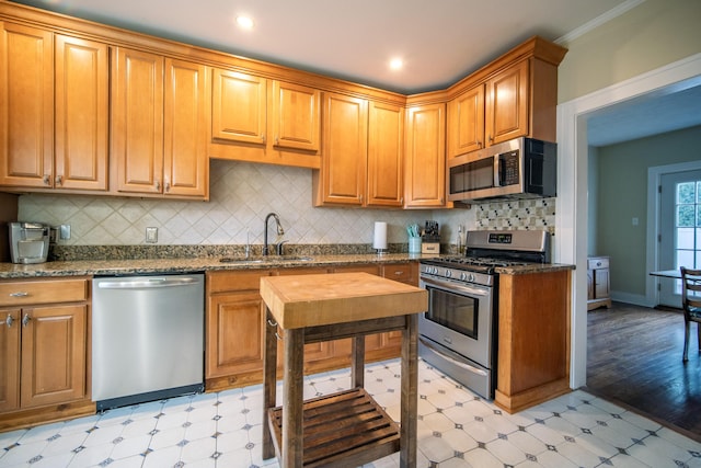 kitchen with stainless steel appliances, light floors, a sink, and brown cabinets