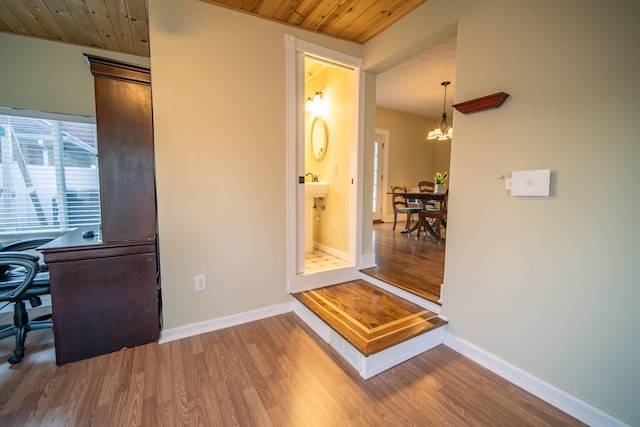 interior space featuring baseboards, wooden ceiling, wood finished floors, and a notable chandelier